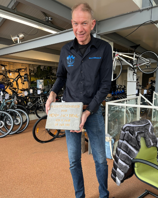 Hans Dral laat een steen van de eerste winkel zien