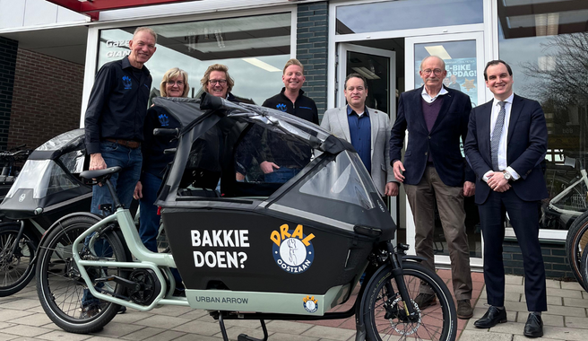 Het college van burgemeester en wethouders poseert met Hans Dral tijdens het bezoek bij Dral Fietsen